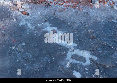 Flaque gelée avec de la glace brisée. Croûte de glace sur les flaques. Fond d'hiver. Flaque d'eau gelée sur la route. En janvier. Flaque gelée et chemin de terre Fermer Banque D'Images