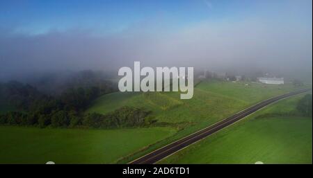 Vue aérienne de brouillard tôt le matin avec les nuages bas au cours de la campagne avec les fermes et les routes rurales, les champs de cultures, Hillsboro, Wisconsin, USA. Banque D'Images