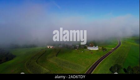 Vue aérienne de brouillard tôt le matin avec les nuages bas au cours de la campagne avec les fermes et les routes rurales, les champs de cultures, Hillsboro, Wisconsin, USA. Banque D'Images