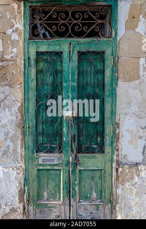 Fortement usé et érodé la porte verte sur un limstone traditionnels maltais construit la maison. Malte, l'Union européenne. Banque D'Images