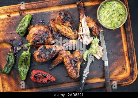 Barbecue traditionnel des Caraïbes poulet jerk ailes et pilons avec une sauce Chimichurri Banque D'Images