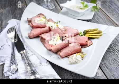 Le déjeuner traditionnel avec des tranches de viande froide et de rosbif sur un gros plan en rémoulade assiette blanche sur une table en bois Banque D'Images