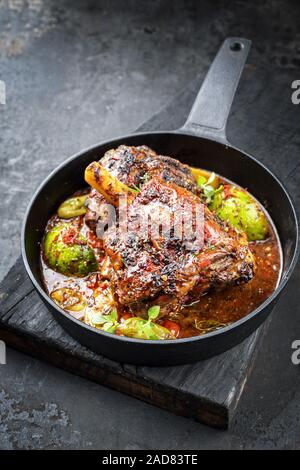 Barbecue traditionnel gigot d'agneau au citron et les tomates en libre dans un poêlon en fonte Banque D'Images