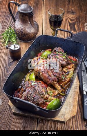 Barbecue traditionnel gigot d'agneau au citron et les tomates en libre dans un vieux poêle Banque D'Images