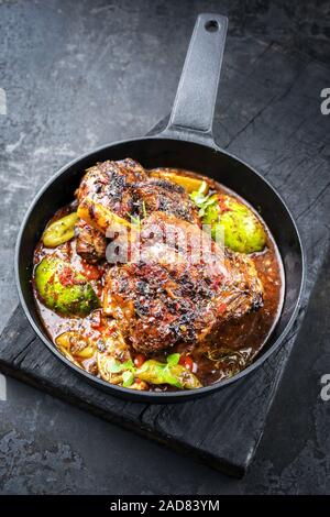 Barbecue traditionnel gigot d'agneau au citron et les tomates en libre dans un poêlon en fonte Banque D'Images