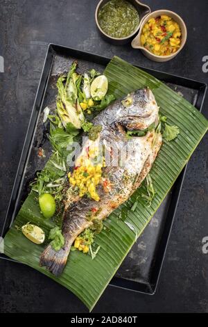 Barbecue frais la daurade royale avec laitue et Chutney de mangues en vue de dessus sur une feuille de banane verte Banque D'Images