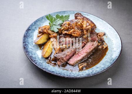 Sec traditionnel de tranches de rôti de boeuf aux oignons frits et les chips de pomme de terre en gros plan sur une assiette avec la sauce brune avec l'exemplaire Banque D'Images