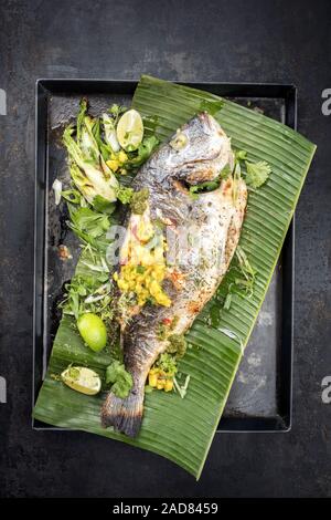 Barbecue frais la daurade royale avec laitue et Chutney de mangues en vue de dessus sur une feuille de banane verte Banque D'Images