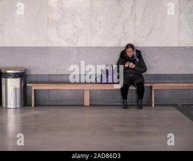 Le parc du Mont-Royal, Montréal, Canada - le 29 novembre 2019. Une femme assise sur un banc et vérifie son portable au Chalet du Mont-Royal près du haut de la Banque D'Images