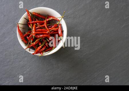 Un bol de chili rouge vif sur un fond gris (vue de dessus avec l'exemplaire de l'espace sur le côté droit et le bas de l'image Banque D'Images