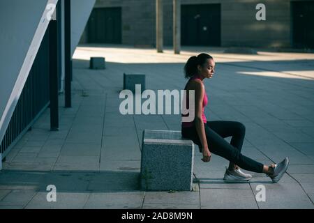 Fatigué de la sportive reposant sur le cube de pierre stock photo Banque D'Images