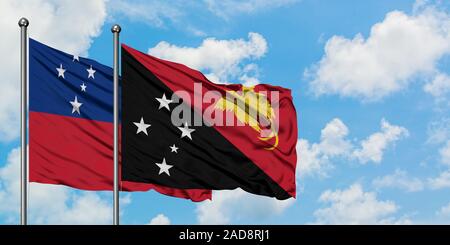 Samoa et en Papouasie-Nouvelle-Guinée drapeaux dans le vent contre ciel bleu nuageux blanc ensemble. Concept de diplomatie, de relations internationales. Banque D'Images