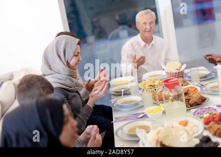 La famille musulmane multiethnique moderne prier avant d'avoir un dîner iftar Banque D'Images