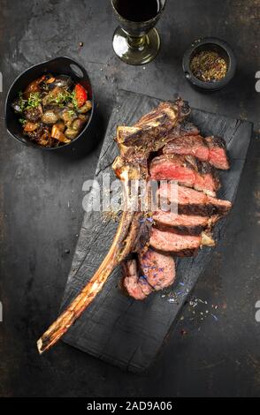 Barbecue traditionnel de sec tomahawk wagyu steak tranché avec la ratatouille comme vue de dessus sur une planche de bois carbonisé rustique Banque D'Images