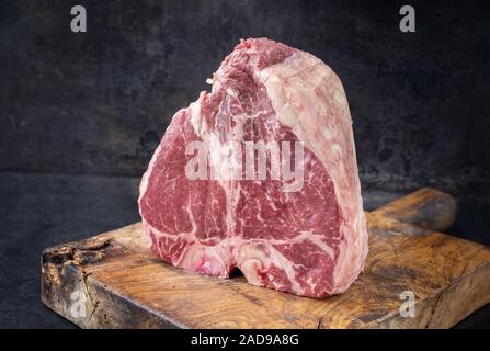 Matières premières traditionnelles porterhouse steak wagyu de sec comme gros plan sur une vieille planche à découper rustique with copy space Banque D'Images