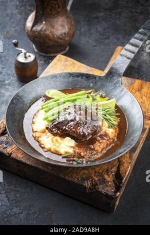 Joues de veau braisées traditionnel allemand en sauce brune avec une purée de pommes de terre et les haricots comme libre dans une casserole en fer forgé Banque D'Images