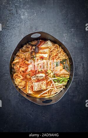 Le kimchi jjigae traditionnel coréen à flanc de porc grillé et ramen comme libre dans un design moderne en fonte japonaise dis torréfaction Banque D'Images