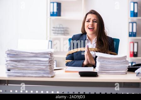 Belle jeune employé attaché avec une corde dans le bureau Banque D'Images