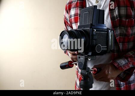 Photo d'un homme adulte détenant un vieux film moyen format vintage et appareil photo sur un trépied. Banque D'Images