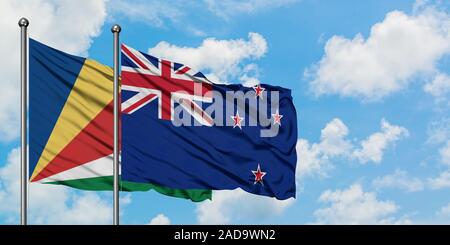 Seychelles et de brandir le drapeau de la Nouvelle-Zélande dans le vent contre ciel bleu nuageux blanc ensemble. Concept de diplomatie, de relations internationales. Banque D'Images