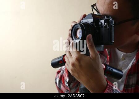 Photo d'un homme adulte détenant un vieux et petit format vintage ou 135mm sur un trépied. Banque D'Images