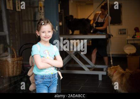 Peu cute girl standing in front of salon de pour les animaux Banque D'Images