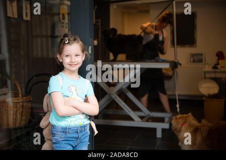 Peu cute girl standing in front of salon de pour les animaux Banque D'Images