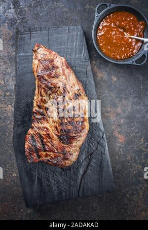 Barbecue de sec tri wagyu steak voyage avec la sauce barbecue comme trempette comme vue de dessus sur une planche de bois carbonisé Banque D'Images