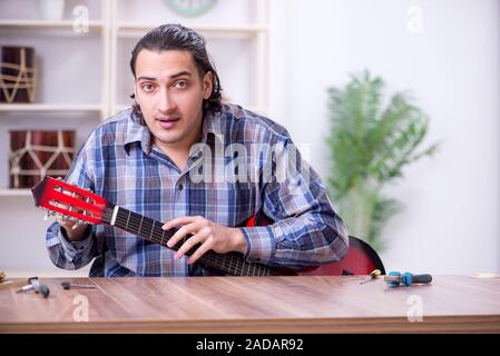 Beau jeune réparateur réparation guitare Banque D'Images