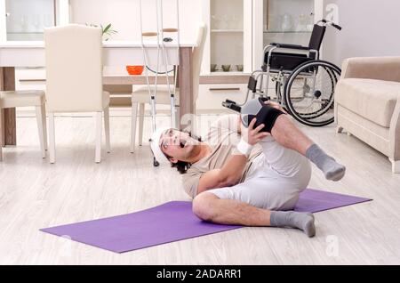 Jeune homme blessé faisant des exercices à la maison Banque D'Images