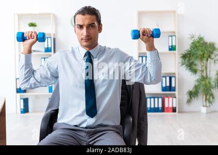 Beau jeune employé faire du sport sur le lieu de travail d'exercices Banque D'Images