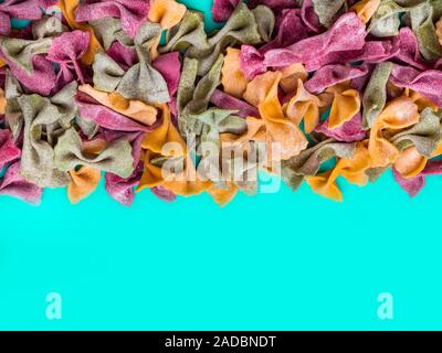Pile de couleur Tri séchées italiennes pâtes farfalle. Différentes couleurs de nœud papillon sur fond de couleur bleu Banque D'Images