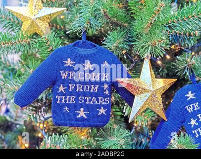 Petit pull bleu et d'étoiles d'or sur un arbre de Noël. Banque D'Images