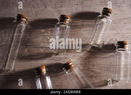 Petits flacons en verre avec couvercle en liège. Bulles vides dans la lumière profilée sur fond en bois, grande bannière, espace pour le design Banque D'Images