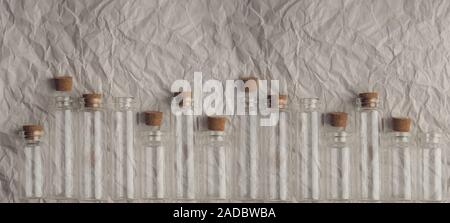 petites bouteilles en verre sur papier froissé, banderole, médecine et recherche. Petits flacons en verre avec couvercle en liège. Banque D'Images
