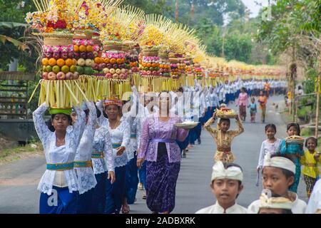 Défilé de vêtements traditionnels des femmes portant des offrandes au temple ou gebogans sur leur tête sur l'île de Bali, Indonésie. Banque D'Images