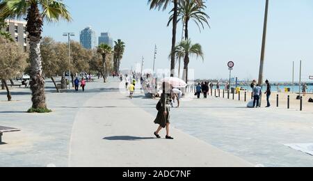 Barcelone, Espagne - 24 avril 2018 : les gens marcher et courir en front de mer, sur la célèbre plage de La Barceloneta à Barcelone, Espagne, avec le Mapfre Banque D'Images