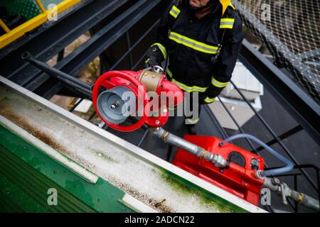 Les détails avec les mains d'un pompier à la tenue d'un système anti-incendie (incendie) sur une hélistation de l'hôpital. Banque D'Images