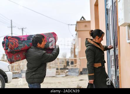 (191204) -- URUMQI, le 4 décembre 2019 (Xinhua) -- Imin et sa femme entrer dans leur nouvelle maison à une zone de réinstallation pour Darya Boyi en ville Comté Yutian, nord-ouest de la Chine, la Région autonome du Xinjiang Uygur, Novembre 18, 2019. Avant de passer à la nouvelle colonie le 17 novembre et le 18 novembre de cette année, la maison d'Imin berger était au coeur de l'Désert Taklimakan, le deuxième plus grand désert de sable dans le monde. Pour des centaines d'années, les ancêtres d'Imin ont installés le long de la rivière Keriya, qui coule du sud au nord jusqu'au cœur de dunes de sable sans fin, en plus comme des doigts et fournissant la soi Banque D'Images