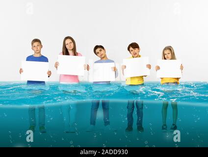 Noyé à la maison. Groupe d'enfants avec des bannières vierge debout dans l'eau de la fonte des glaciers, le réchauffement climatique. L'écologie, de l'environnement concept. Sauver la planète pour les générations futures, arrêter de dénaturer la nature. Banque D'Images