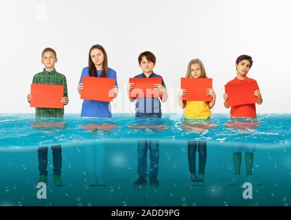 Noyé à la maison. Groupe d'enfants avec des bannières vierge debout dans l'eau de la fonte des glaciers, le réchauffement climatique. L'écologie, de l'environnement concept. Sauver la planète pour les générations futures, arrêter de dénaturer la nature. Banque D'Images