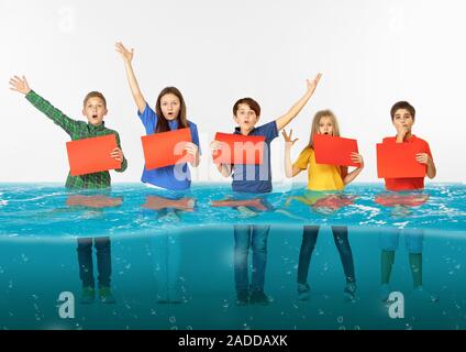 Noyé à la maison. Groupe d'enfants avec des bannières vierge debout dans l'eau de la fonte des glaciers, le réchauffement climatique. L'écologie, de l'environnement concept. Sauver la planète pour les générations futures, arrêter de dénaturer la nature. Banque D'Images