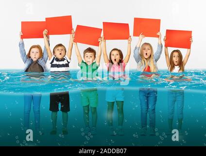 Noyé à la maison. Groupe d'enfants avec des bannières vierge debout dans l'eau de la fonte des glaciers, le réchauffement climatique. L'écologie, de l'environnement concept. Sauver la planète pour les générations futures, arrêter de dénaturer la nature. Banque D'Images