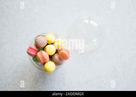 Mini macarons gâteaux dans un paquet glisser sur un fond gris, vue du dessus Banque D'Images