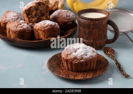 Flocons d'avoine muffins aux bananes saupoudrée de sucre glace sur une plaque et de noix de coco 1 tasse de lait, l'orientation horizontale Banque D'Images