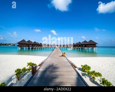 Passerelle au-dessus de l'eau peu profonde à l'eau, bungalows à l'île de South Male Atoll, Maldives Banque D'Images