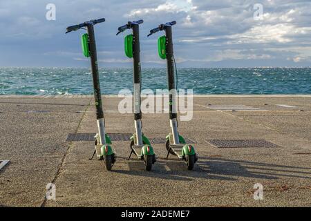 Garé vert et noir le covoiturage La Chaux-S electric scooters sans passager à bord de l'eau à côté de la mer à Thessalonique, en Grèce. Banque D'Images