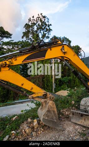 L'excavatrice moderne sur le site de construction avec Ciel de coucher du soleil. Grande pelle à chenilles debout sur une colline avec une herbe verte. Machines pour un Banque D'Images