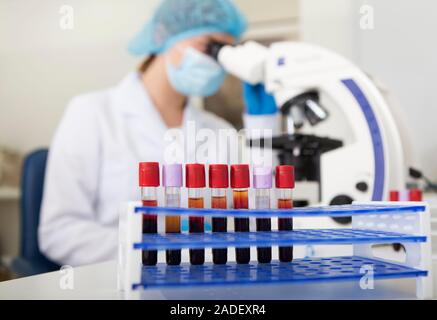 Masque flou en femme à la recherche de microscope pour l'analyse des échantillons de sang Banque D'Images