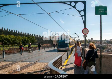 Le tramway électrique moderne faisant partie du réseau des transports publics à Porto, Portugal traverse la rivière Douro sur le dessus de la Pont Dom Luis I un double-D Banque D'Images